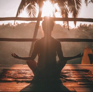 woman meditating facing the sun