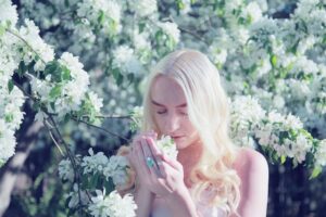 woman smelling flowers with her eyes closed