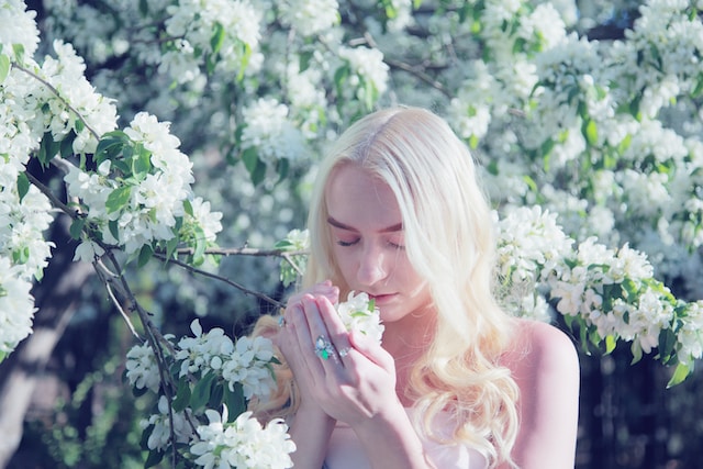 woman smelling flowers with her eyes closed