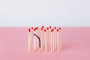 A collection of matches standing up with one burnt out match curled over.