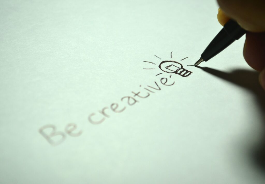 "Be creative" written in pencil on a piece of paper with a lightbulb drawn next to the words.