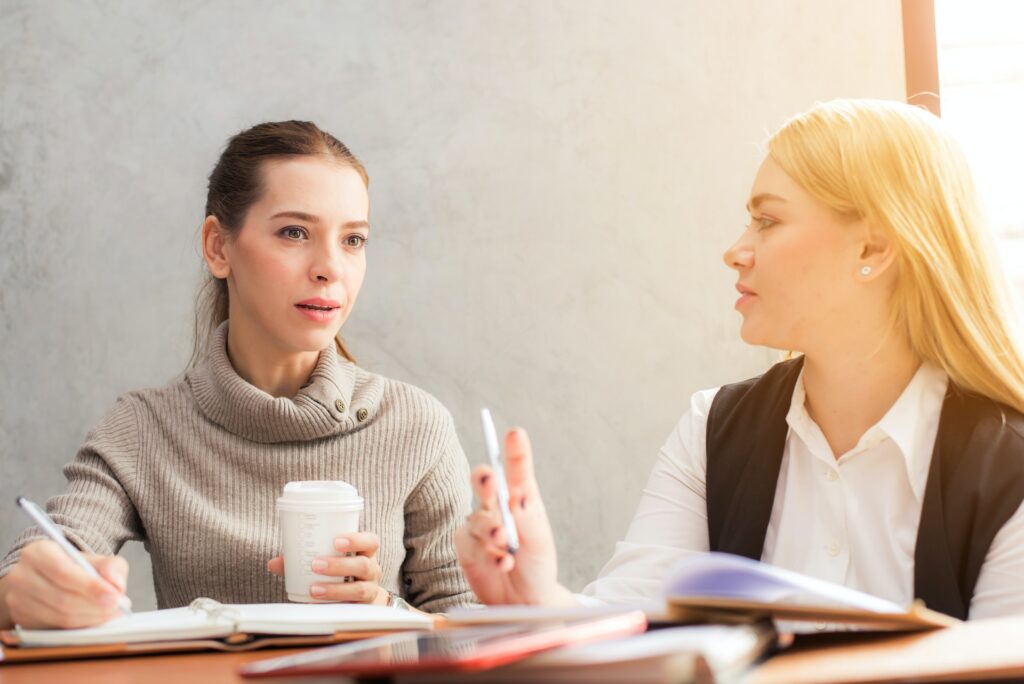 Two women talking and holding pens