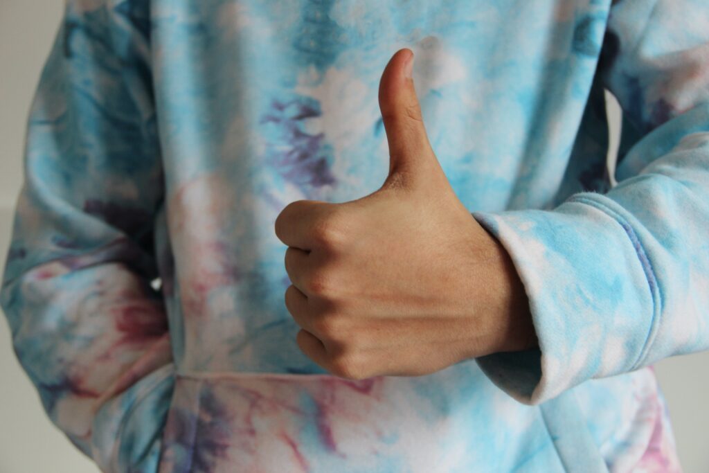 Person with a tie-dye hoodie doing a thumbs up for approval