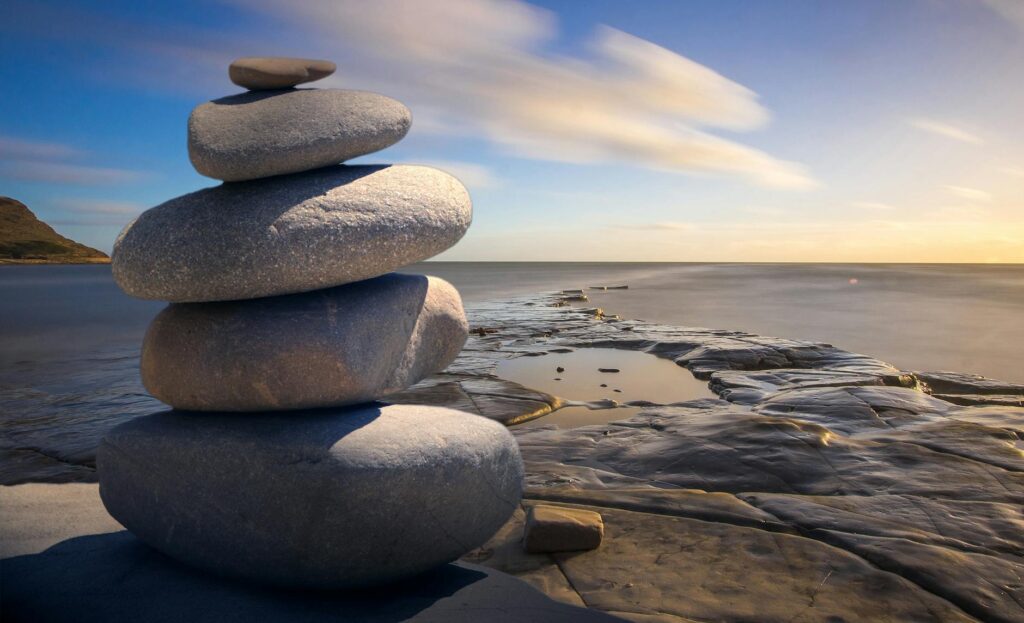 A stack of rounded oval stones sit in front of the ocean.