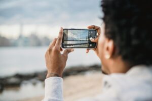 A man takes a picture of the beach with his phone.