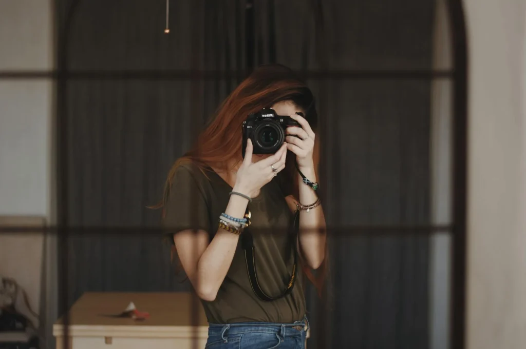 A woman holds a camera up to her face about to take a photo.