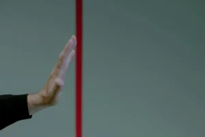 A hand reaches into frame from the left. A red line runs down the middle. The hand is held up before the red line, not crossing over.