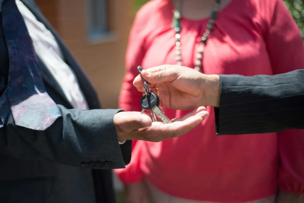 A close up of a hand passing over a set of keys to an open hand.