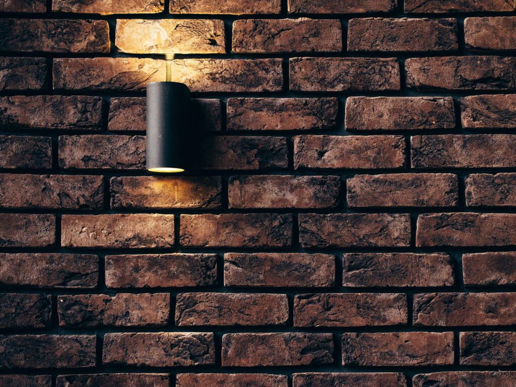 A dark red brick wall with a wall light emitting a soft glow.