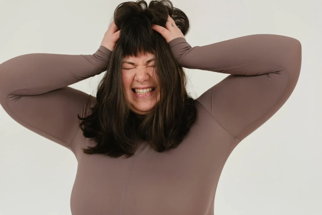 A woman grips her hair with an frustrated grimace.